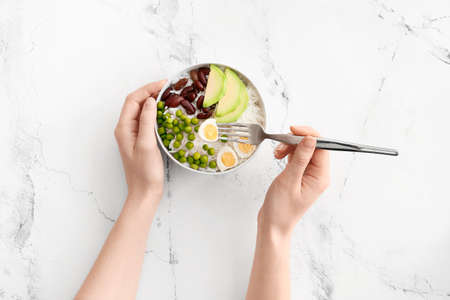 Woman eating tasty rice with beans and vegetables on white background