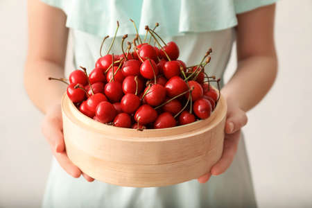 Woman with bowl of sweet cherry, closeup