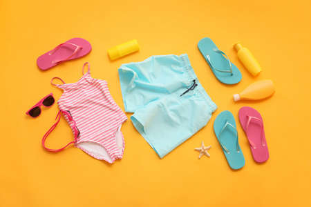 Set of beach accessories with children swimsuits on color backgroundの写真素材