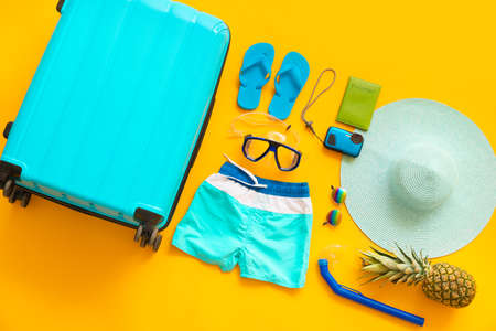 Set of beach accessories with suitcase on color background. Concept of rest abroad