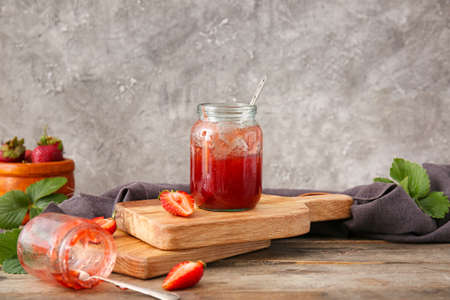 Jars with tasty strawberry jam on table