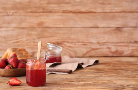 Jar of tasty strawberry jam on wooden backgroundの写真素材