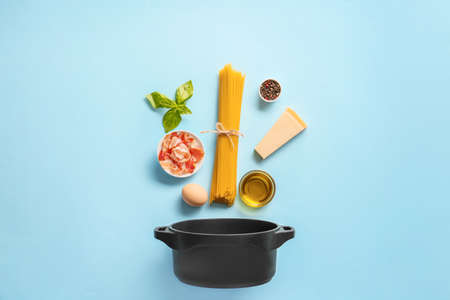 Ingredients for tasty pasta carbonara and pot on color backgroundの写真素材