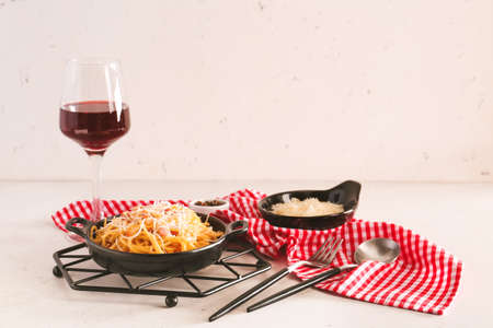 Frying pan with tasty pasta carbonara and glass of wine on tableの写真素材