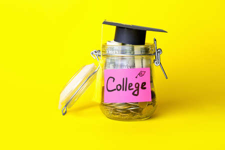 Jar with savings for education and graduation hat on color backgroundの写真素材