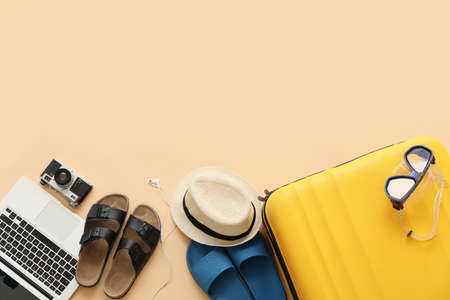 Suitcase with beach accessories and laptop on color backgroundの写真素材