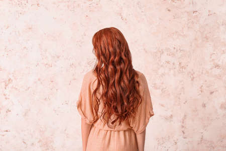 Beautiful young redhead woman on light background, back viewの写真素材