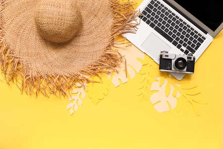 Composition with beach hat, photo camera and laptop on color backgroundの写真素材