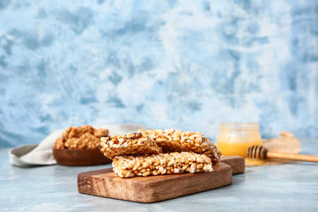 Board with crispy rice bars on color background