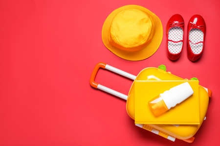 Composition with suitcase and little girl accessories on color background. Travel conceptの写真素材