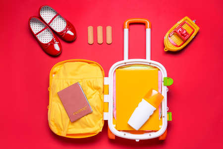 Composition with suitcase and little girl accessories on color background. Travel conceptの写真素材