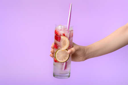 Hand with glass of fresh strawberry lemonade on color backgroundの写真素材
