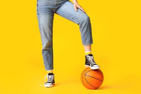 Beautiful young woman in jeans clothes and with ball on color background
