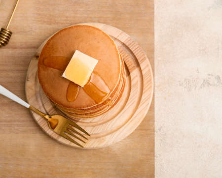 Tasty pancakes with butter and honey on tableの写真素材
