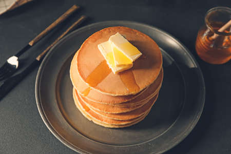 Tasty pancakes with butter and honey on tableの写真素材