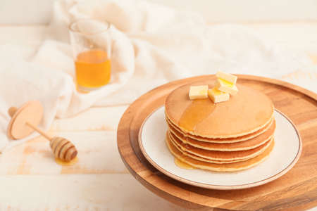 Tasty pancakes with honey and butter on table