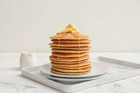 Tasty pancakes with butter and honey on tableの写真素材