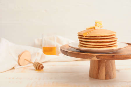 Tasty pancakes with honey and butter on tableの写真素材