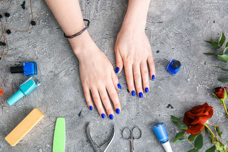 Female hands with beautiful manicure and supplies on grunge backgroundの写真素材