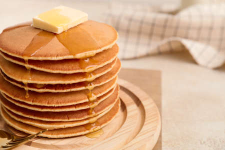 Tasty pancakes with butter and honey on board