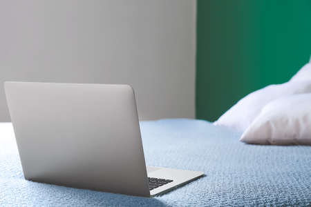 Modern laptop on bed in roomの写真素材