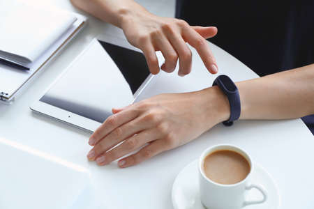 Woman using fitness tracker at table, closeup