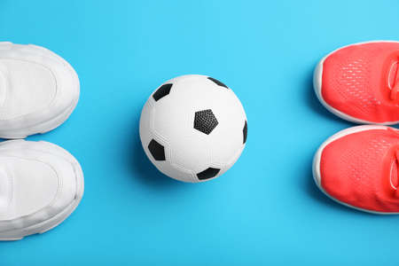 Soccer ball and shoes on color background