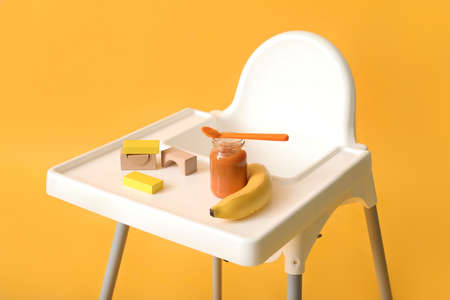 Baby highchair with food and toys on color backgroundの写真素材