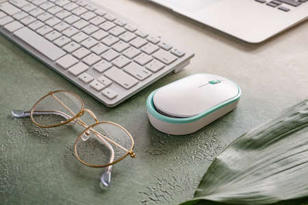 Modern PC mouse, keyboard and glasses on table