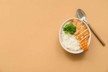Bowl with boiled rice and chicken on color backgroundの写真素材