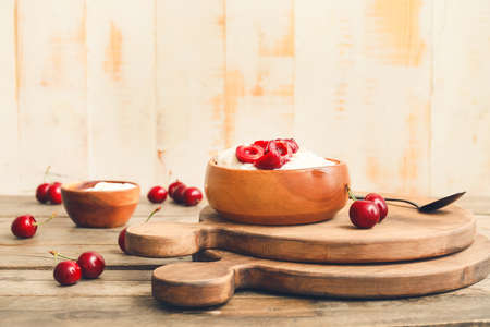 Bowl with boiled rice and cherry on tableの写真素材
