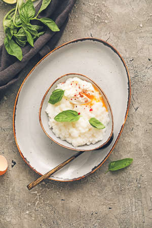 Bowl with boiled rice and egg on gray background