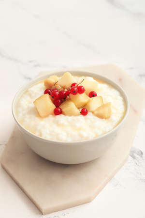 Bowl with boiled rice and fruits on tableの写真素材