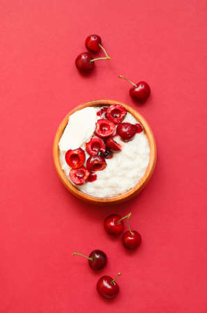 Bowl with boiled rice and cherry on color backgroundの写真素材