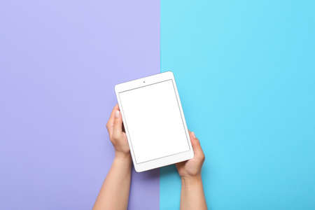 Woman holding tablet computer on color background