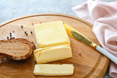 Butter, knife and bread on wooden boardの写真素材