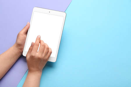 Woman using tablet computer on color backgroundの写真素材