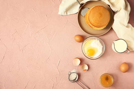 Tasty pancakes with ingredients on color backgroundの写真素材
