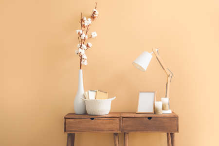 Wicker basket with lamp and cotton flowers on table in roomの写真素材