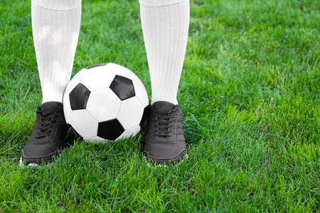 Football player with soccer ball on green grass outdoors