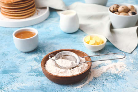 Plate with flour for pancakes on color background