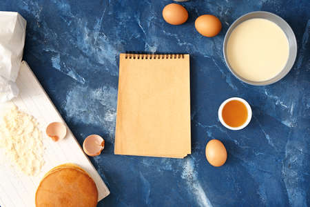 Ingredients for pancakes and notebook on color backgroundの写真素材