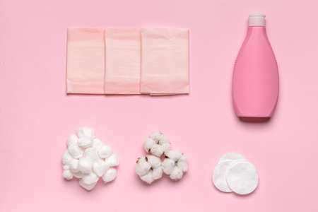Cotton balls with cosmetic and menstrual pads and bottle of shampoo on color backgroundの写真素材