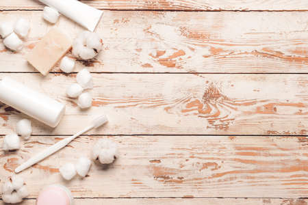 Cotton flowers with balls and cosmetics on wooden background