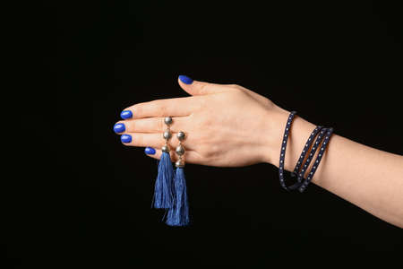 Hand with beautiful manicure holding earrings on dark backgroundの写真素材