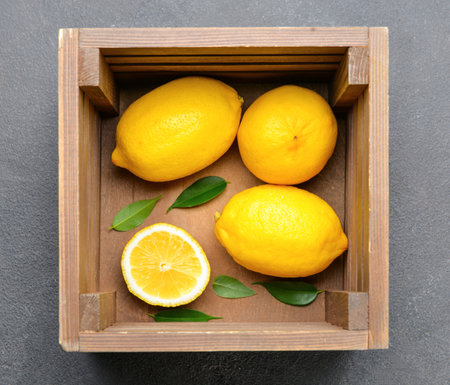 Wooden box with lemons on gray backgroundの写真素材