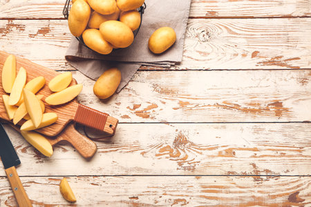Raw potatoes with knife and cutting boards on wooden tableの写真素材