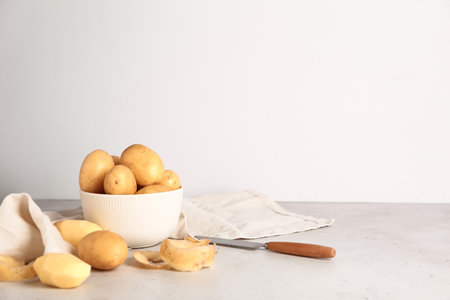 Bowl with raw potatoes on light backgroundの写真素材