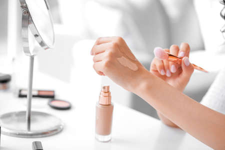 Beautiful young woman applying foundation at home, closeupの写真素材