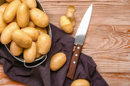 Wicker basket with raw potatoes on wooden tableの写真素材